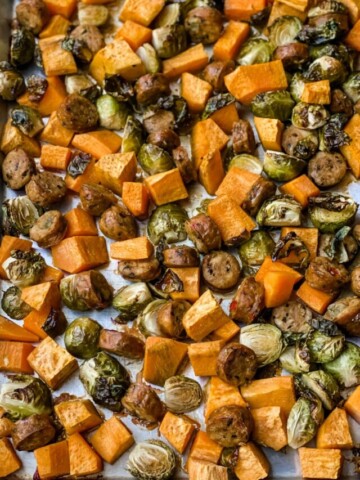 closeup of baked veggies and sausage on a sheet pan.