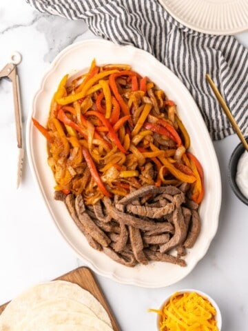 overhead picture of steak fajitas, peppers, and onion on a platter.